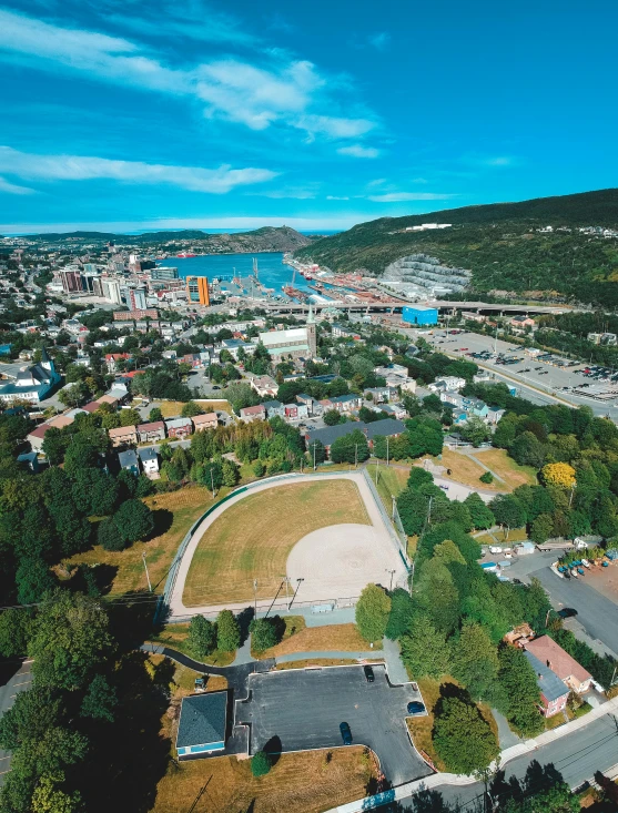 an aerial view of a city with a baseball field, by Terese Nielsen, pexels contest winner, harbour in background, stålenhag, cornell, slide show