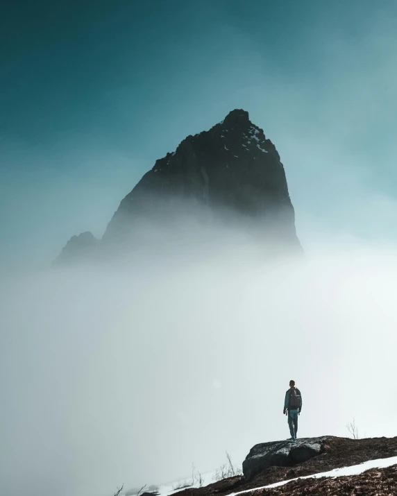a man standing on top of a mountain in the fog, pexels contest winner, photo of shiprock, cyan fog, minimalist photo, photo of a man