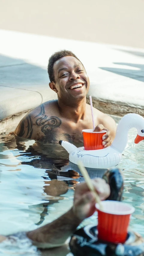 a man in a pool with an inflatable duck, by Carey Morris, pexels contest winner, man is with black skin, holding a drink, lil wayne, serene smile