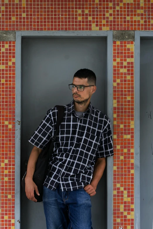 a man standing in the doorway of a building, an album cover, inspired by Eddie Mendoza, unsplash, altermodern, wearing a plaid shirt, with glasses and goatee, non binary model, in sao paulo