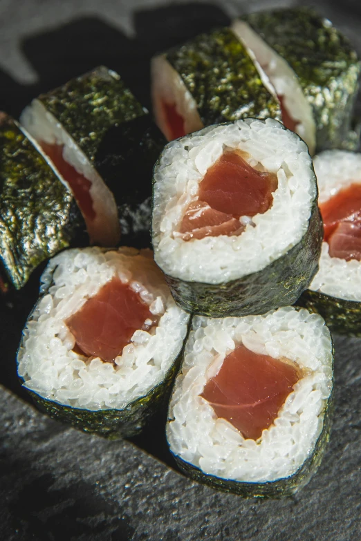 a bunch of sushi sitting on top of a black plate, inspired by Maki Haku, sōsaku hanga, 6 pack, dynamic closeup, aged 2 5, reds