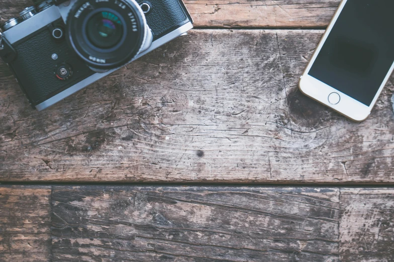 a camera and a cell phone on a wooden table, trending on pexels, art photography, vintage soft grainy, featured art, photograph ”, medium format