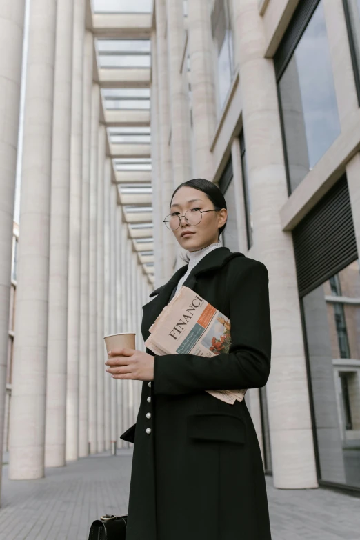 a woman standing in front of a tall building, inspired by Fei Danxu, trending on unsplash, renaissance, holding a book, wearing causal black suits, thom browne, holding a baguette