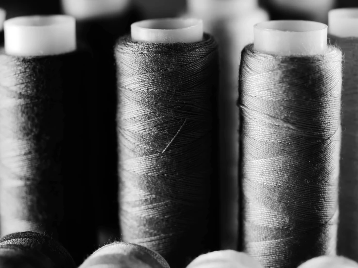a bunch of spools of thread sitting on top of each other, a black and white photo, unsplash, renaissance, black clothing, industries, detached sleeves, tiffany dover