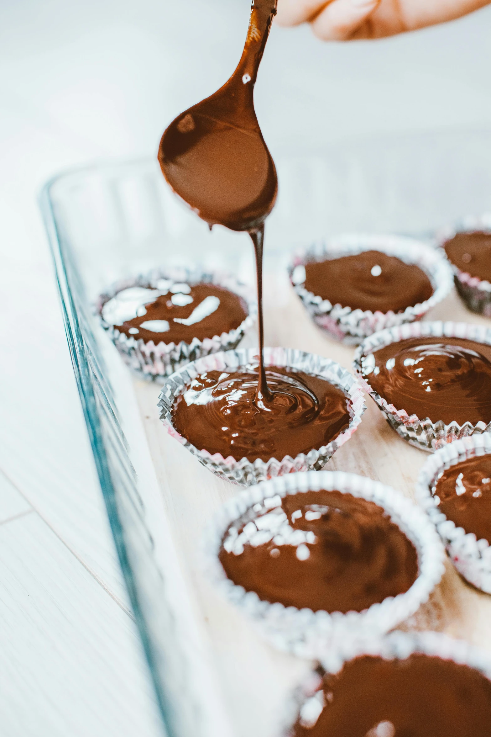 a person dipping chocolate into a tray of cupcakes, pexels, essence, made of glazed, billowy, open top