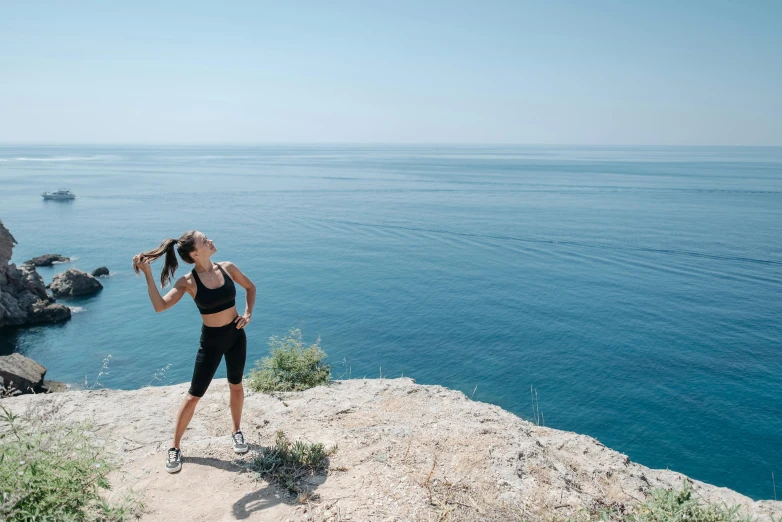 a woman standing on top of a cliff next to the ocean, workout, avatar image, costa blanca, profile image