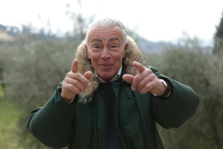 a man in a parka giving a thumbs up, by Francesco Furini, pexels, antipodeans, olive trees, white haired, still image from tv series, looking surprised