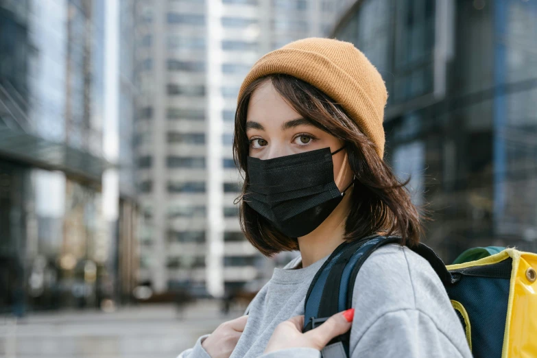 a woman wearing a face mask in a city, trending on pexels, with black beanie on head, manuka, avatar image, student