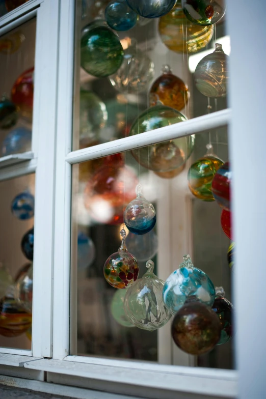 a window filled with lots of colorful glass ornaments, elliot alderson, square, natural soft light, three - quarter view