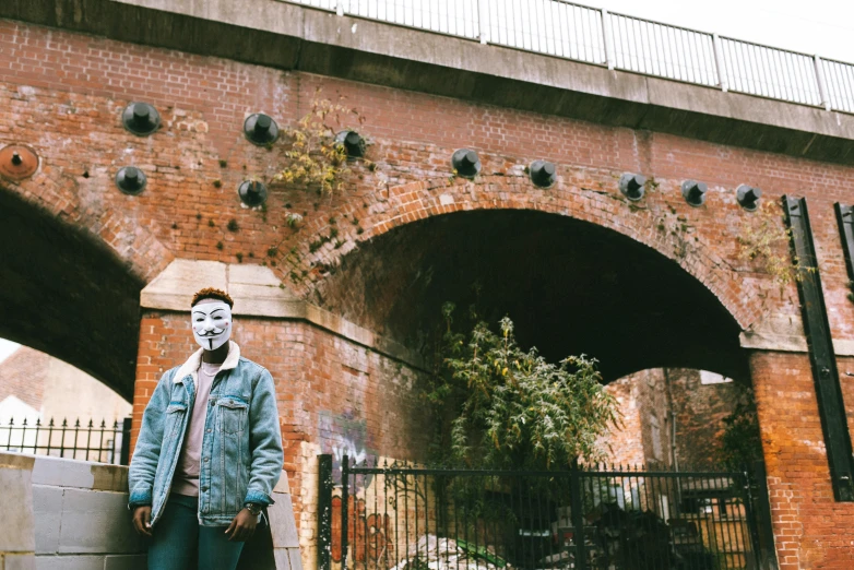 a man standing in front of a brick bridge, unsplash, graffiti, michael myers mask, 2 0 0 0's photo, grime, indie film