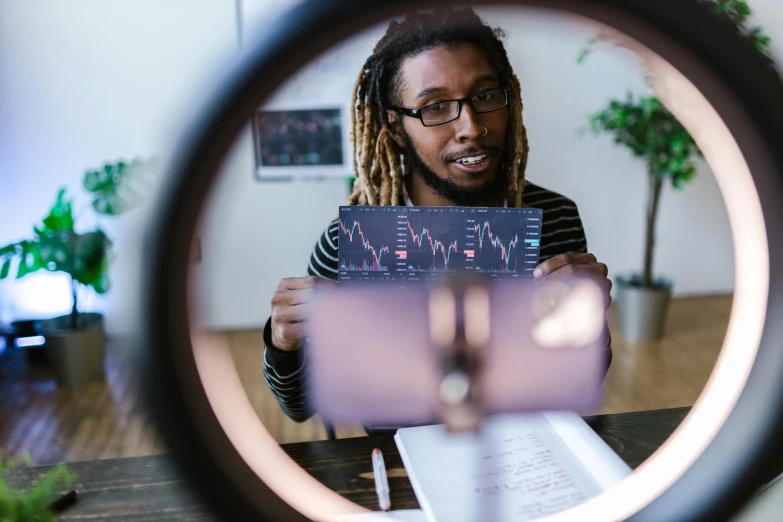 a man with dreadlocks looking through a magnifying lens, a hologram, pexels contest winner, displaying stock charts, teaching, with anamorphic lenses, 🦑 design