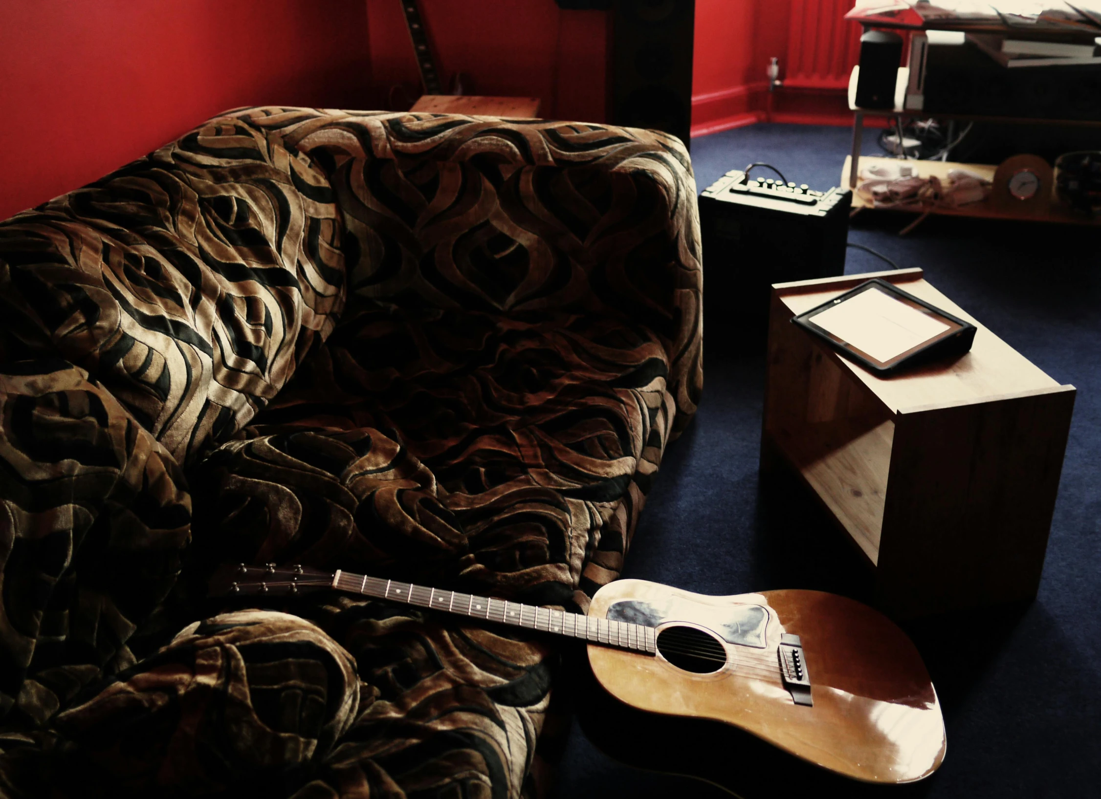 a guitar sitting on top of a couch in a living room, private press, red room, lachlan bailey, studio setup, in the backrooms