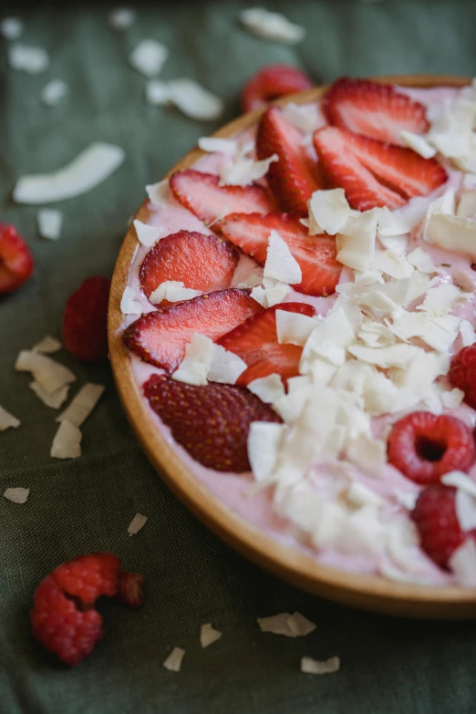 a bowl of yogurt topped with strawberries and coconut, inspired by Barthélemy Menn, pizza on a table, pink, zoomed in, handcrafted