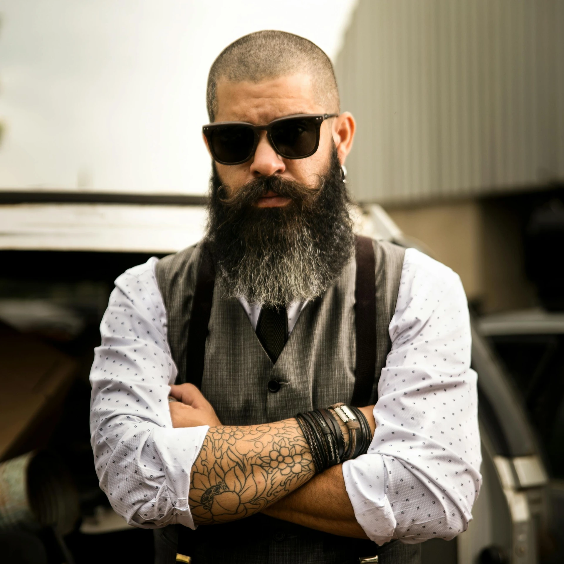 a man with a beard standing in front of a car, brown buzzcut, well dressed, inked, commercially ready