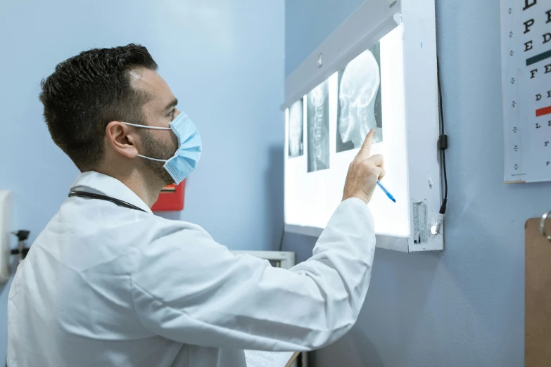 a man in a lab coat is looking at an x - ray, pexels contest winner, surgical gown and scrubs on, 15081959 21121991 01012000 4k, profile image, tourist photo