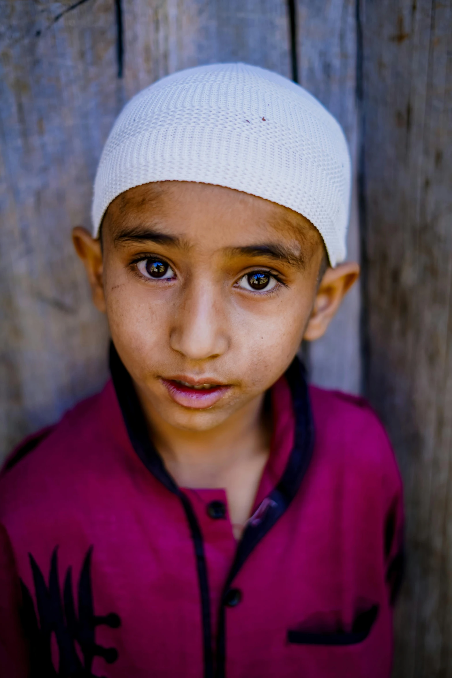 a close up of a child wearing a hat, inspired by Steve McCurry, hurufiyya, an arab standing watching over, shaven face, on center