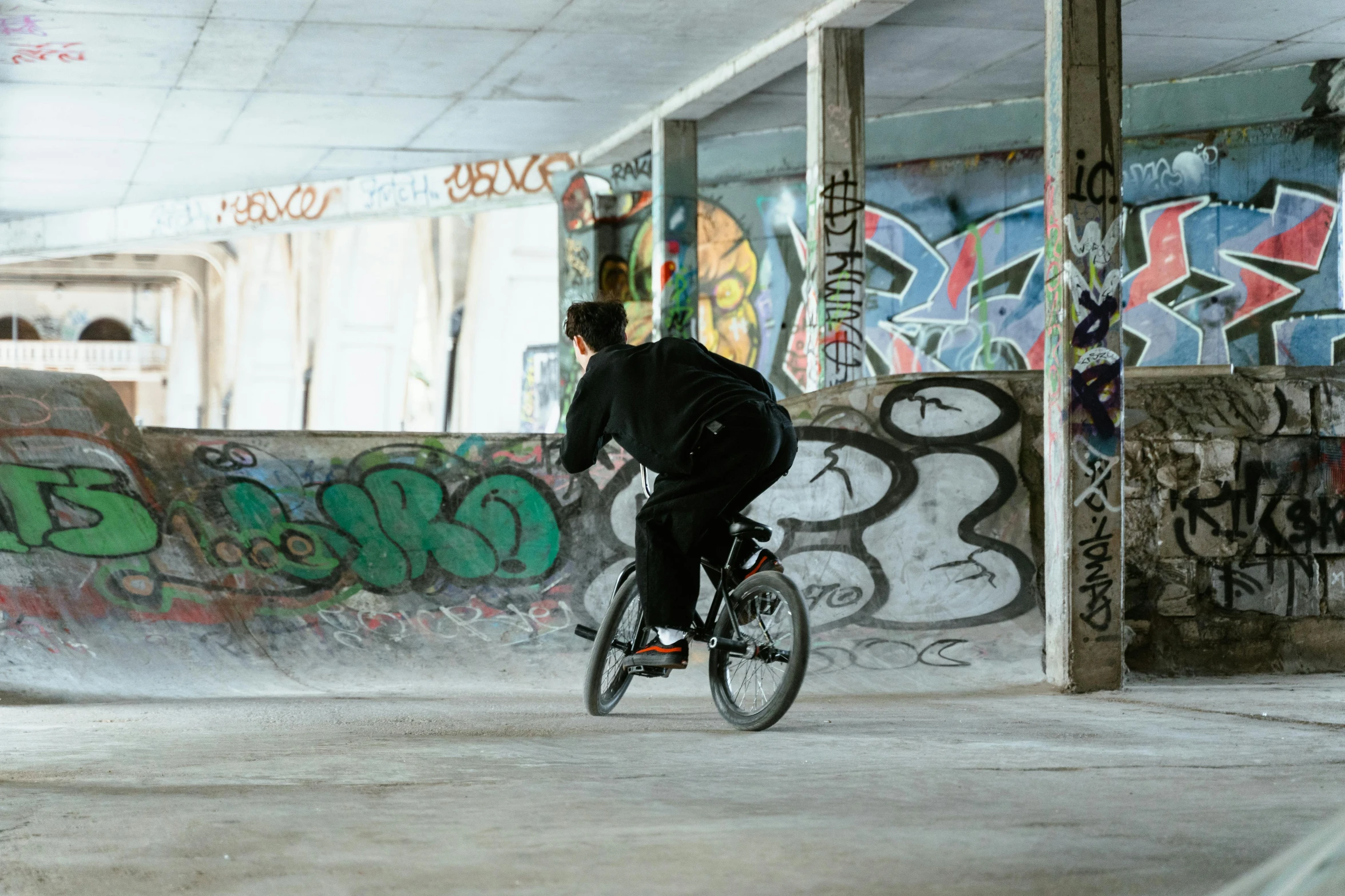 a man riding a bike in an abandoned building, inspired by Seb McKinnon, unsplash, graffiti, at a skate park, yung lean, mid - action, kids