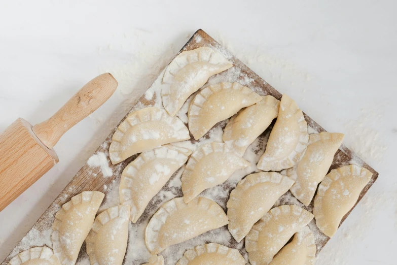 a wooden cutting board topped with dough next to a rolling pin, mingei, 9 peacock tails, thumbnail, dessert, bandoliers