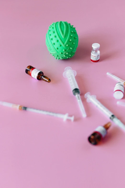 an assortment of medical supplies on a pink surface, a picture, by Nicolette Macnamara, trending on pexels, syringes, candy decorations, overdose, looking from shoulder