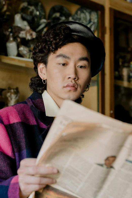 a man sitting at a table reading a newspaper, an album cover, inspired by Hirohiko Araki, trending on pexels, huge earrings and queer make up, berets, wonbin lee, curls on top