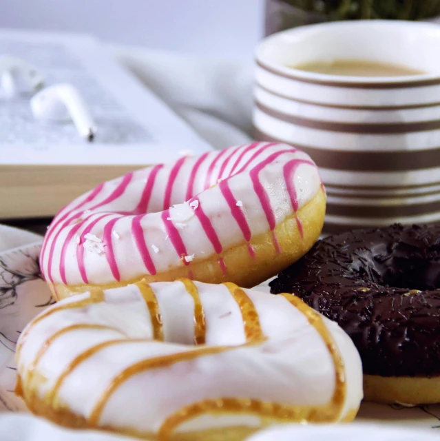 a white plate topped with three donuts next to a cup of coffee, by Dietmar Damerau, pexels, hurufiyya, brown and magenta color scheme, black white pink, chocolate, glazed