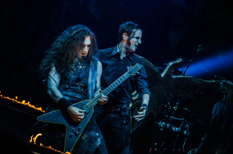 a man standing next to a woman holding a guitar, by Micha Klein, pexels contest winner, symbolism, black metal concert flyer, playing guitar onstage, kamelot album cover, avatar image