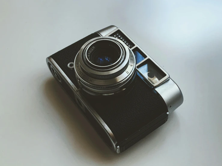 a camera sitting on top of a table, on a pale background, ((photorealistic)), eye - level medium - angle shot