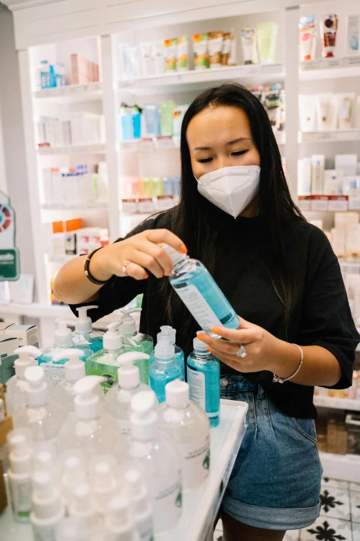 a woman wearing a face mask in a store, pexels, process art, holding a bottle, pharmacy, jen yoon, college