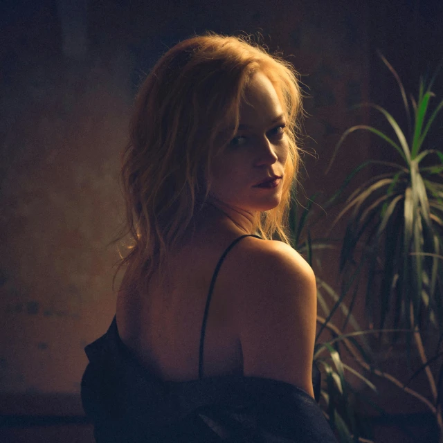 a woman sitting in front of a potted plant, a picture, inspired by Elsa Bleda, unsplash, renaissance, portrait of nicole kidman, standing in a dimly lit room, album cover, back light