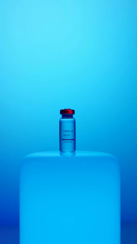 a blue bottle sitting on top of a table, a hologram, holding syringe, blue colors with red accents, front facing shot, thumbnail