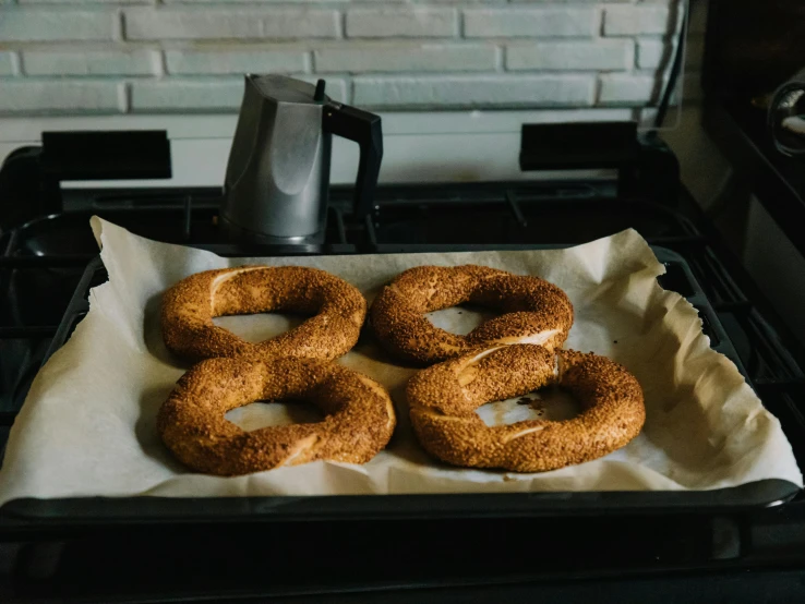 a tray of bagels sitting on top of a stove, by Carey Morris, pexels contest winner, hurufiyya, shaped like torus ring, 🚿🗝📝, full-body, cardboard