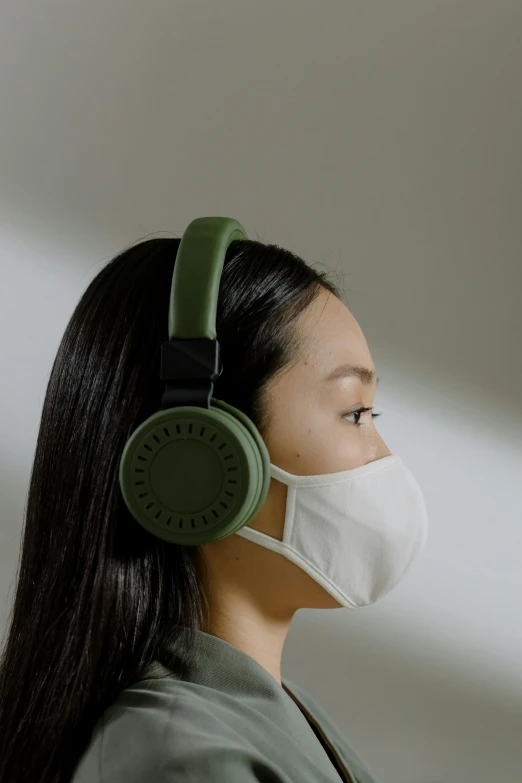 a woman wearing a face mask and green headphones, trending on pexels, bauhaus, beige, made of rubber, asia, facing front