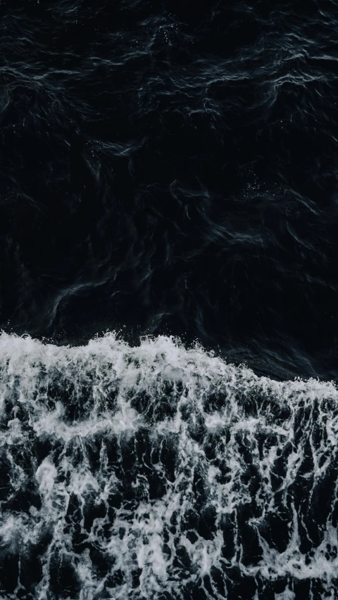 a black and white photo of a body of water, an album cover, by Elsa Bleda, unsplash contest winner, turbulent sea, drone footage, trending on vsco, dark blue water