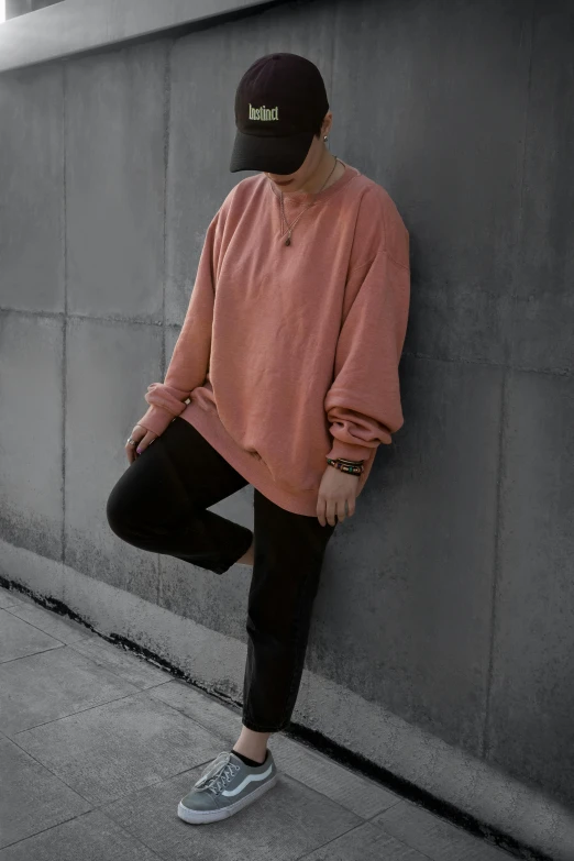 a man leaning against a wall wearing a hat, inspired by jeonseok lee, trending on pexels, aestheticism, long orange sweatshirt, faded pink, fullbody photo, very comfy]