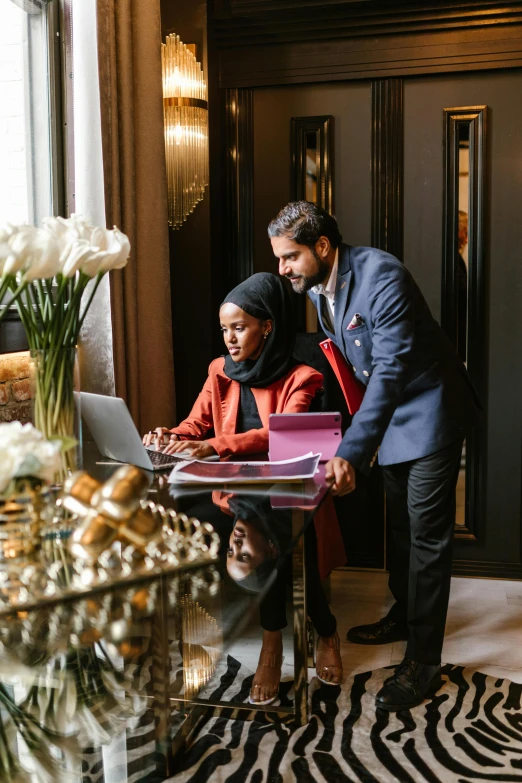 a man and a woman are looking at a laptop, by Adam Saks, pexels contest winner, hurufiyya, sheikh mohammed ruler of dubai, paris hotel style, press shot, instagram story