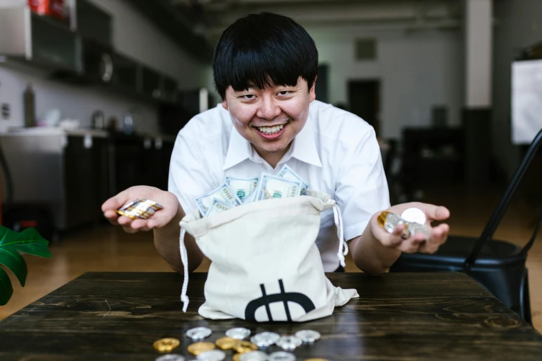 a man sitting at a table with money in front of him, by Jang Seung-eop, pexels contest winner, holding a gold bag, jontron, mei-ling zhou, press shot