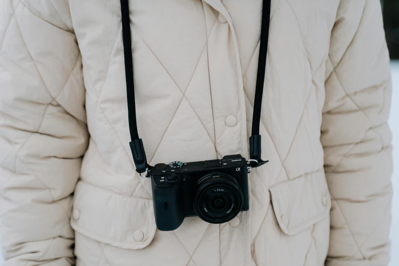 a person standing in the snow with a camera, by Nina Hamnett, unsplash, wrapped in leather straps, a black choker, wearing jacket, sony camera