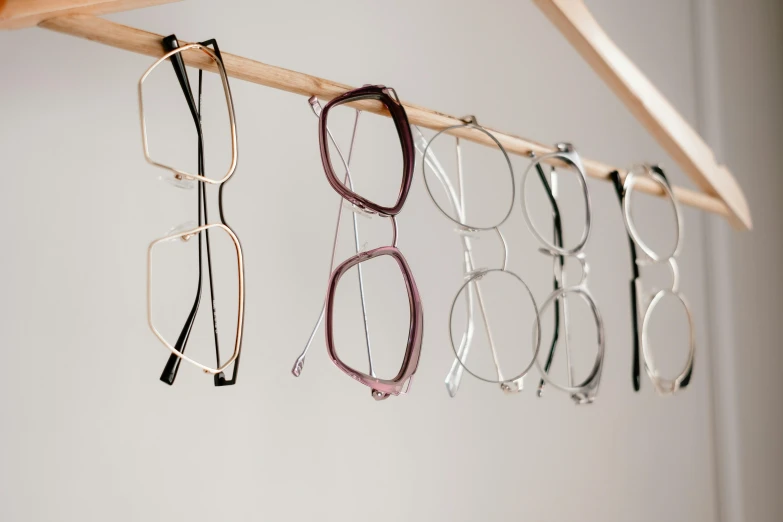 a rack with several pairs of glasses hanging from it, trending on pexels, minimalism, in square-rimmed glasses, press shot, sustainable materials, low - angle shot