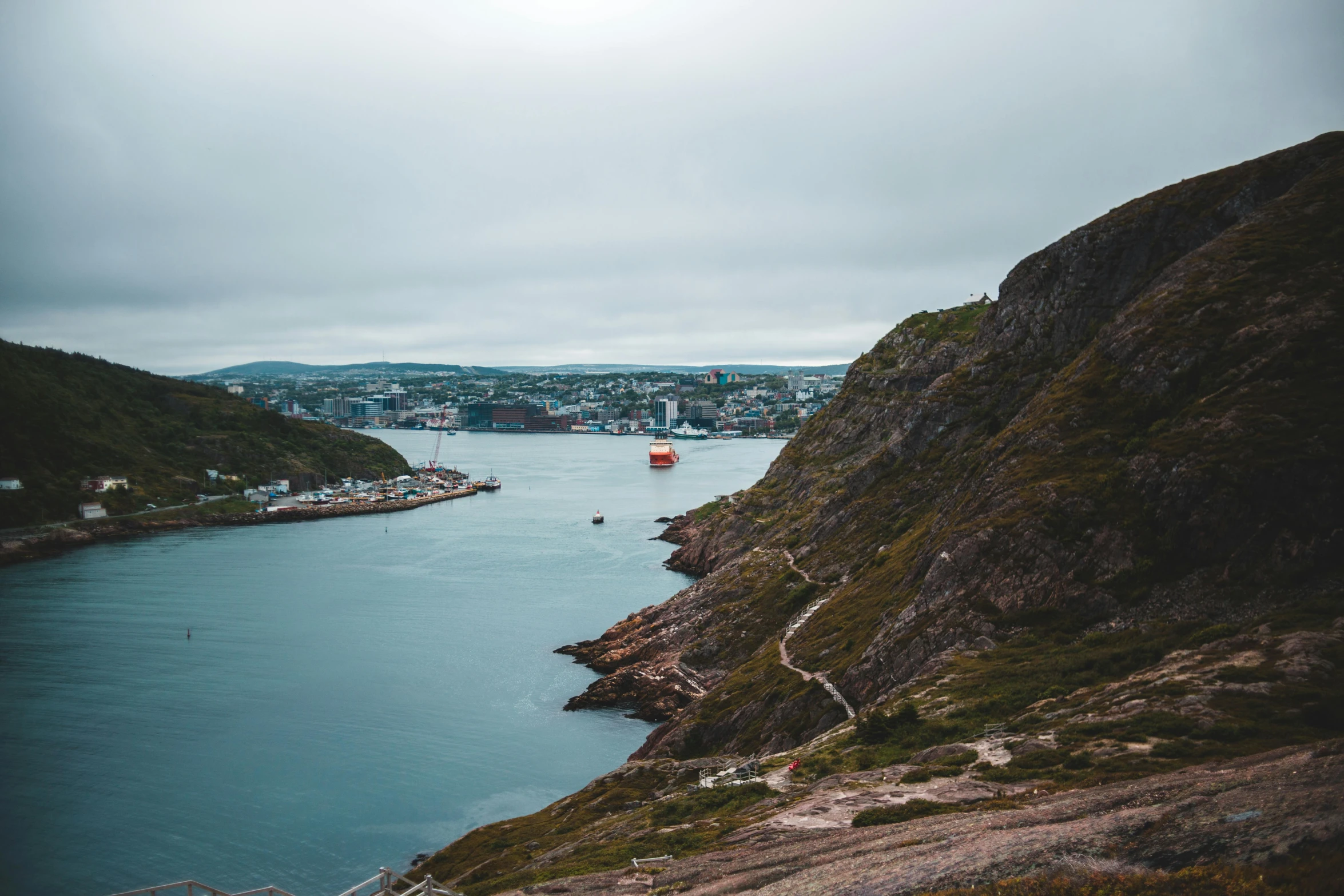 a large body of water sitting on top of a lush green hillside, a photo, by Jesper Knudsen, pexels contest winner, ships in the harbor, brown, gungnir, conde nast traveler photo