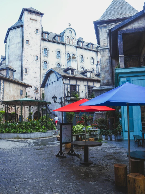 a couple of umbrellas sitting on top of a cobblestone street, a detailed matte painting, inspired by Albert Joseph Pénot, unsplash, food stalls, musee d'orsay 8 k, inside a castle courtyard, st cirq lapopie