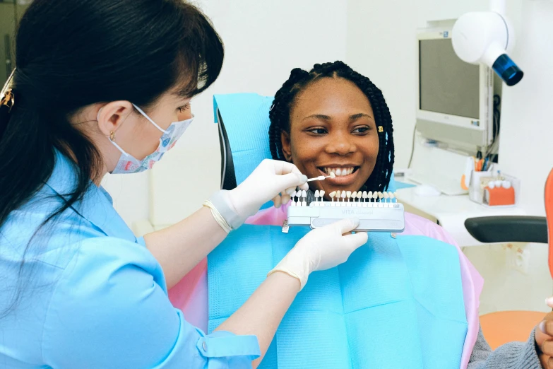 a woman getting her teeth examined by a dentist, a colorized photo, by Elaine Hamilton, pexels contest winner, dark black skin tone, gradient brown to white, crown of white lasers, dominant wihte and blue colours