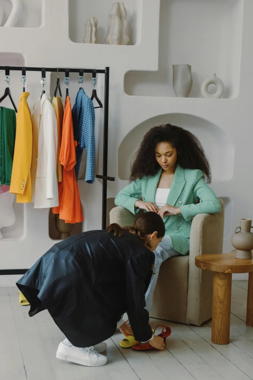 a woman standing next to a woman sitting in a chair, trending on pexels, future inflatable jacket, busy room, ashteroth, video