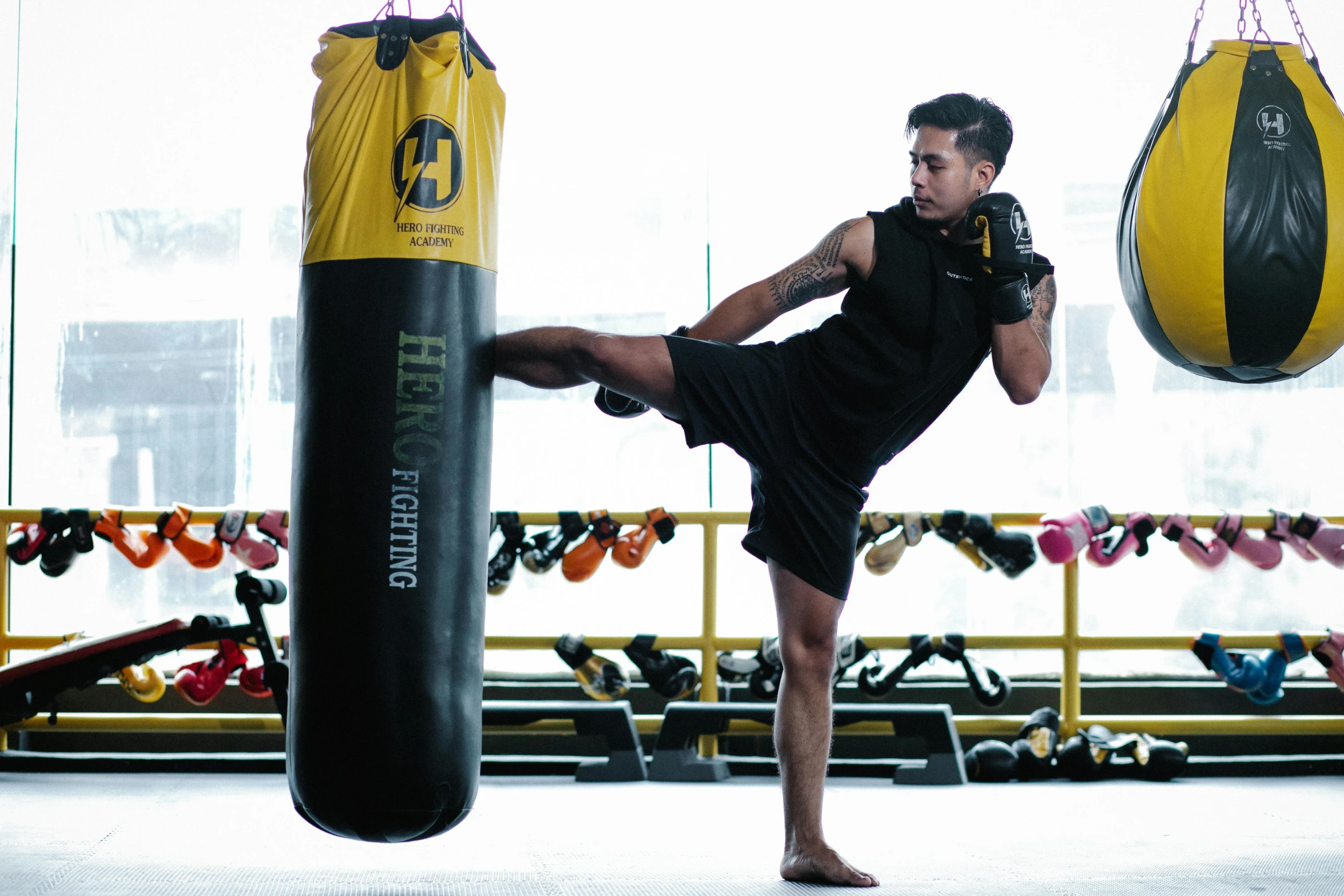 a man kicking a punching bag in a gym, instagram, hurufiyya, yellow and black color scheme, heroengine, official store photo, manila