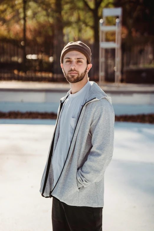 a man standing on a skateboard in a parking lot, a portrait, inspired by Drew Tucker, unsplash, he also wears a grey beanie, wearing a track suit, portrait mode photo, promotional image