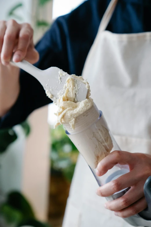 a person in an apron holding a scoop of ice cream, mayonnaise, subtle detailing, loosely cropped, large tall