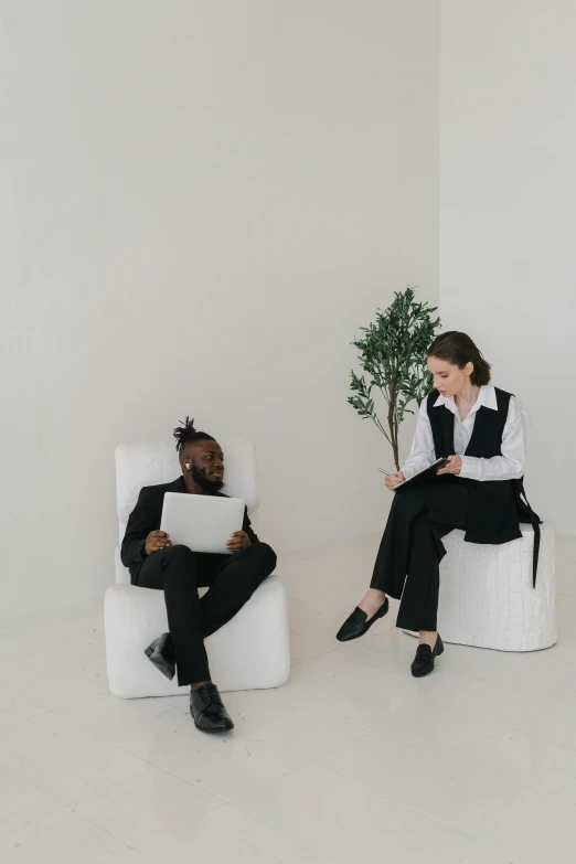 two women sitting in chairs in a white room, pexels contest winner, two men in black, sitting on a tree, ready for a meeting, black man