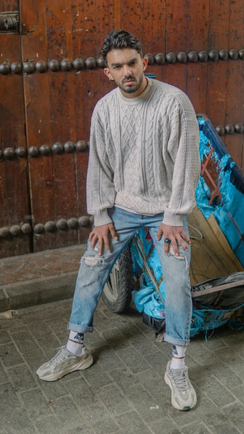 a man standing next to a pile of luggage, an album cover, pexels, happening, baggy jeans, wearing casual sweater, 14 yo berber boy, portrait mode photo