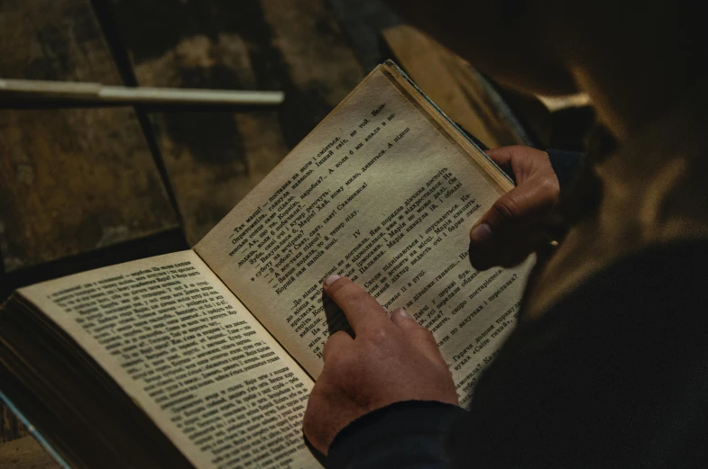 a person reading a book on a wooden table, pexels contest winner, renaissance, movie still from blade runner, holding a book, unreadable text, lit from above