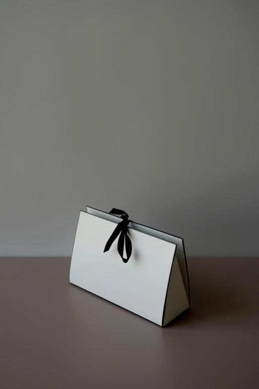 a close up of a box with a bow on it, by Adam Saks, minimalism, glossy white metal, bag, slate, ( ivory black )