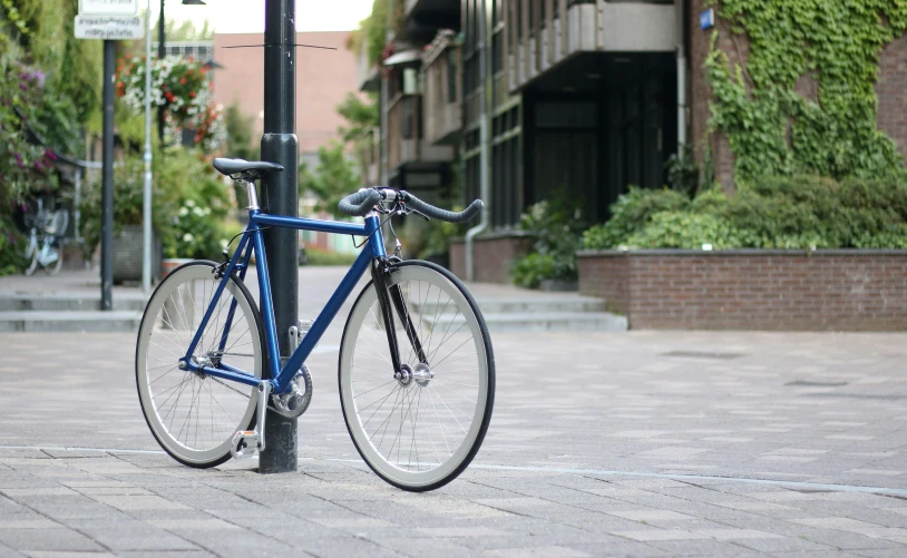 a blue bicycle is chained to a pole, unsplash, utrecht, aerodynamic frame, [ 4 k photorealism ], bulky build